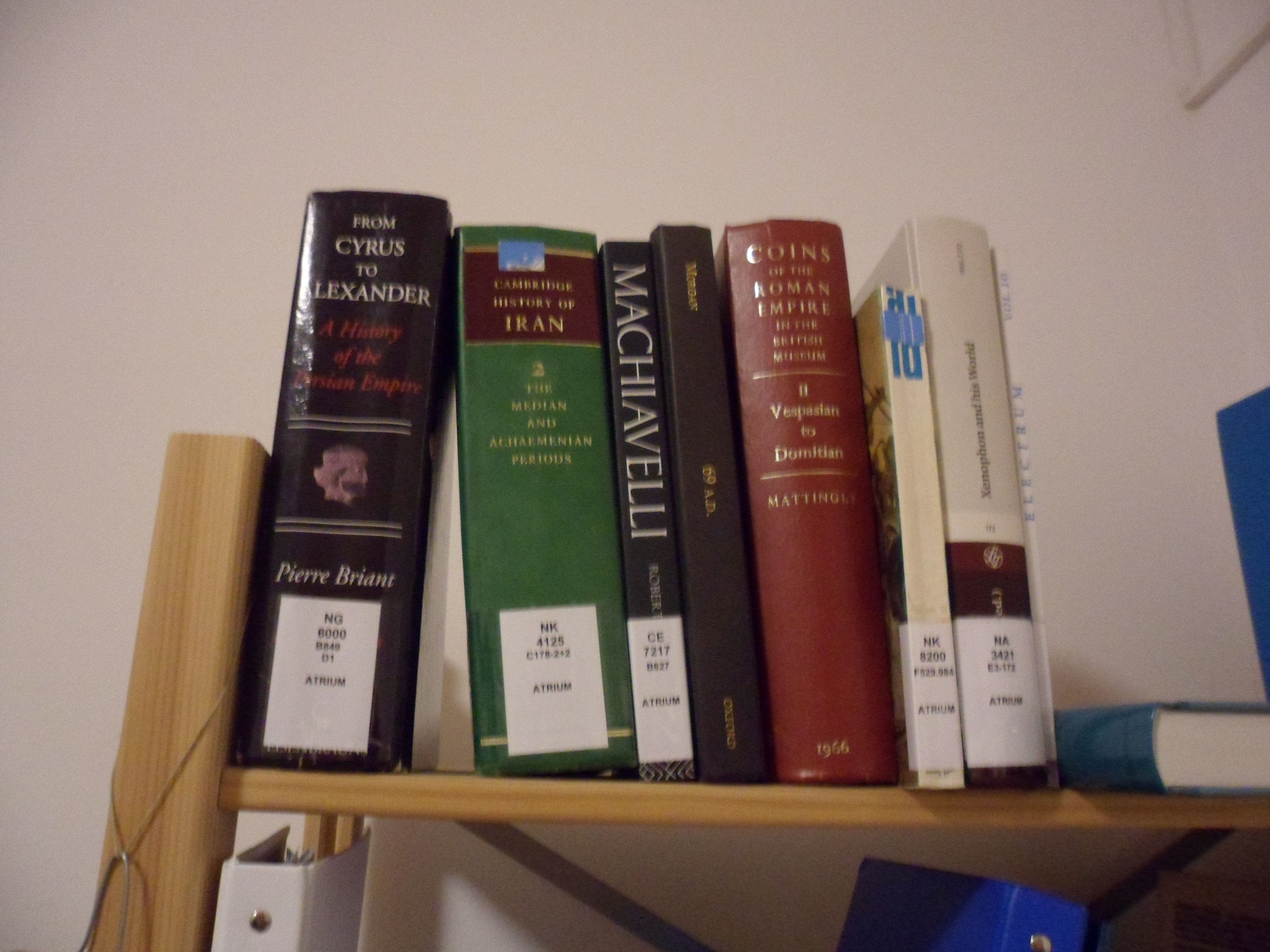 Some books on a shelf including Pierre Briant's History of the Persian Empire and volume two of the Cambridge History of Iran