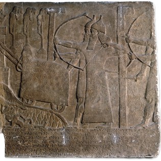 Stone relief with soldiers with spears and shields running up ladders placed against a city while a wheeled battering ram with a tower attacks its walls and archers shoot from behind pavises