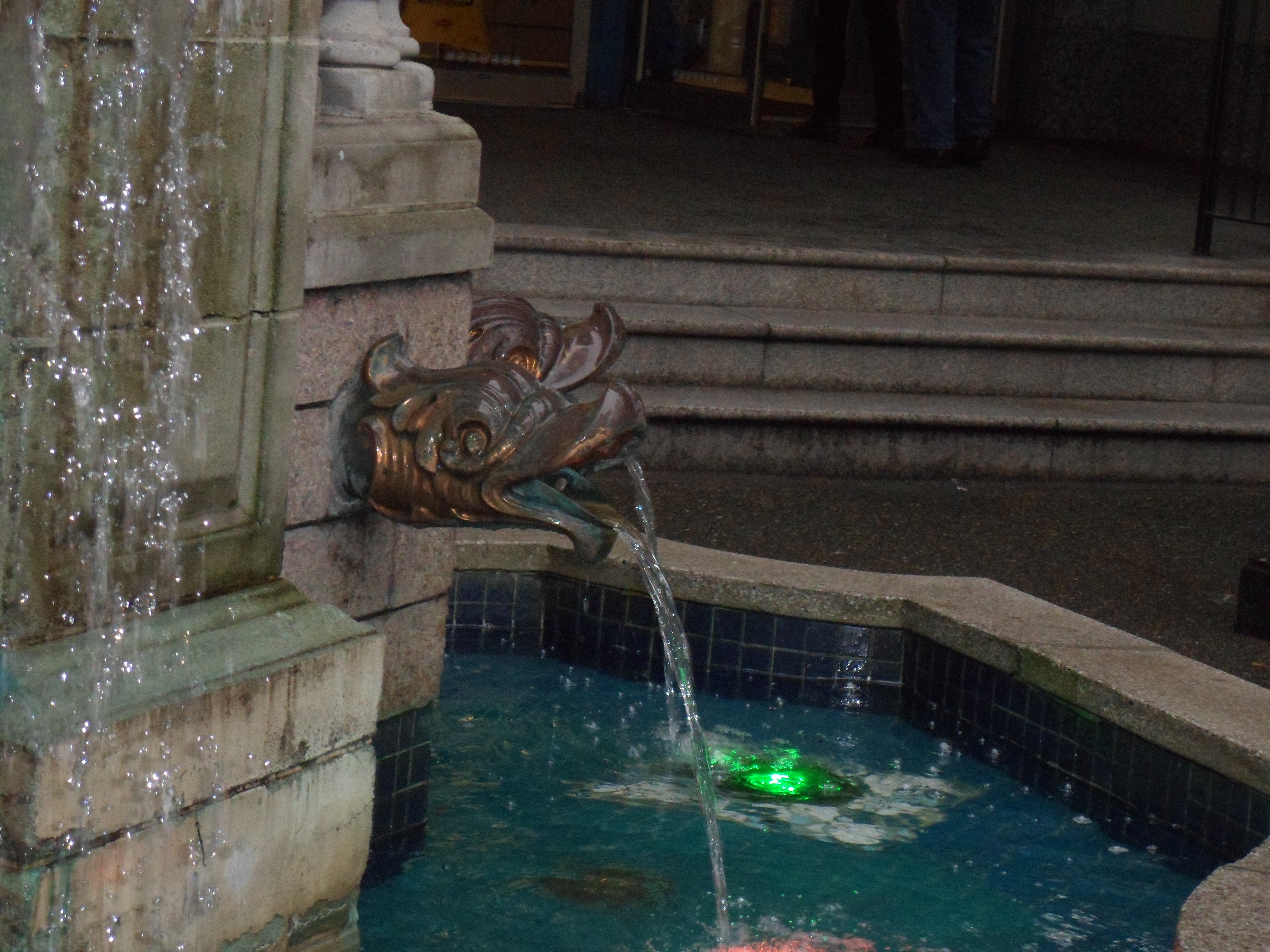 A stone fountain with copper spouts in the forms of fish-heads