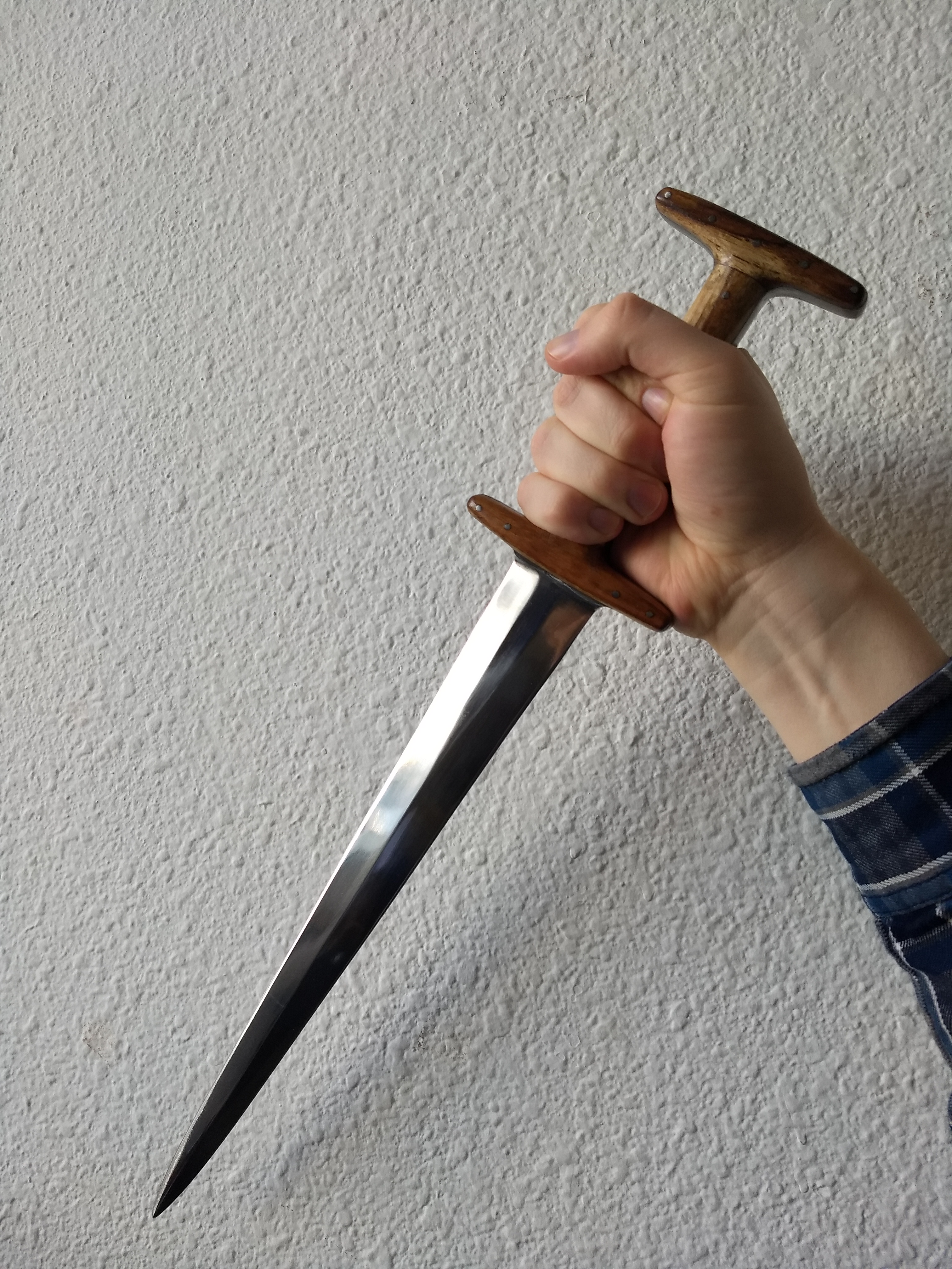 A hand gripping a dagger with a wooden hilt