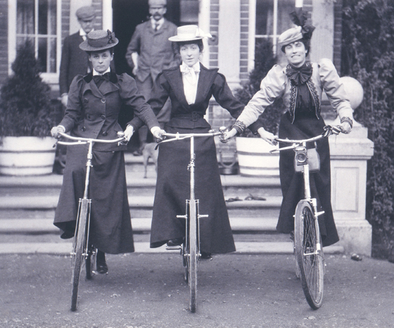 Three women in dressnding on bicycles with straight handlebars