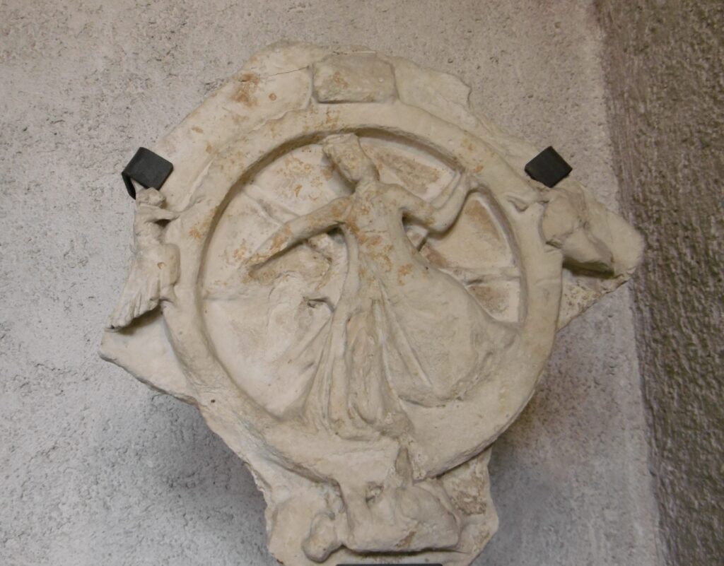 a damaged stone carving of a wheel of fortune