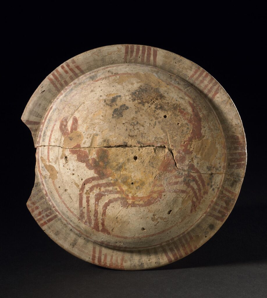 a terracotta model shield painted with a red crab on a white background