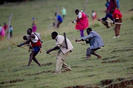 a group of archers in Western clothes and back quivers move down a grassy hill